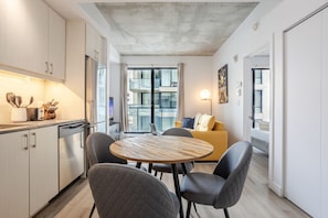 A modern kitchen with a dining area, a sofa, and a view of the city.