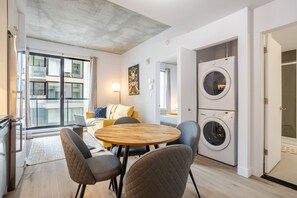 Um apartamento moderno com área de jantar, sofá, máquina de lavar e varanda com vista.