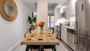 A modern kitchen with stainless steel appliances, a wooden dining table with chairs, and a large mirror on the wall.
