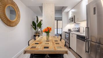 A modern kitchen with stainless steel appliances, a wooden dining table with chairs, and a large mirror on the wall.