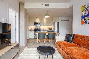 A compact living space with a kitchenette, a dining area, a sofa, and a television.