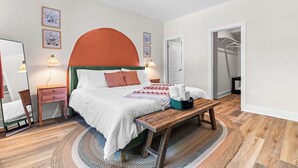 Une chambre à coucher comprenant un lit, des tables de chevet, un banc, un miroir et une armoire.