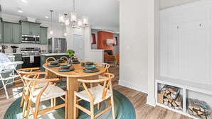 Une cuisine moderne avec des meubles en bois, un îlot central et un coin repas comprenant une table ronde et des chaises.
