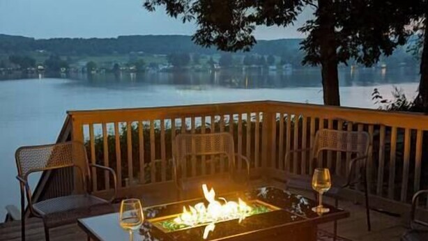 A deck with a glass-top table, two chairs, and a fire feature. - Lake Front Reverie- Waneta Lake, NY (Dundee)