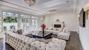 Ein luxuriöses Wohnzimmer mit einem großzügigen, L-förmigen Sofasessel, einem Marmor-Couchtisch und einem Kamin.