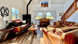 Un salón espacioso con chimenea, sofás de cuero y un alto techo con tragaluces.