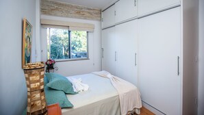 A bedroom with a bed, a window, a wardrobe, and a decorative wall piece.