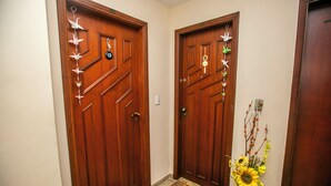 Two wooden doors with decorative elements, a doormat, and a vase with sunflowers.