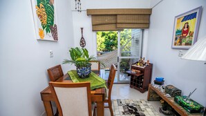 A dining area with a wooden table, chairs, a green tablecloth, and a potted plant.