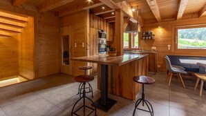 A wooden cabin interior with a kitchen, bar area, and seating.