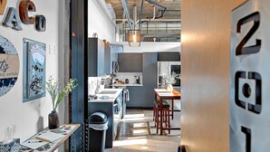 Une cuisine moderne dotée d’un îlot central, d’un coin repas avec une table et des chaises en bois, et offrant une vue sur l’espace de vie adjacent.