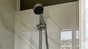 Een moderne douche met een handdouche en een kraan op de muur.