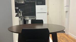 Een kleine keuken met een eettafel en stoelen, een inbouwoven, magnetron en koelkast.
