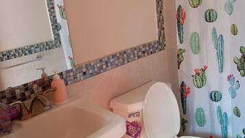 Een badkamer met een wastafel, toilet en douchegordijn met een cactusthema.