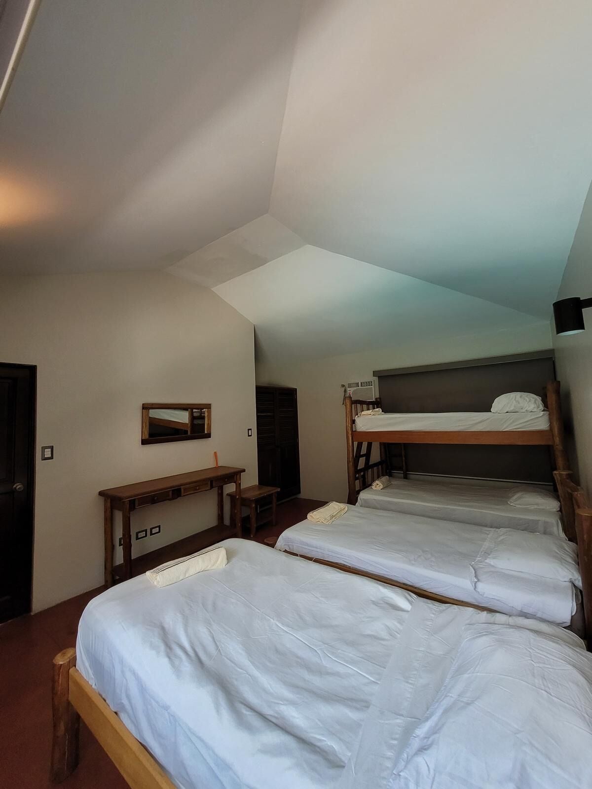 Une chambre de dortoir avec des lits superposés, un bureau et un miroir.