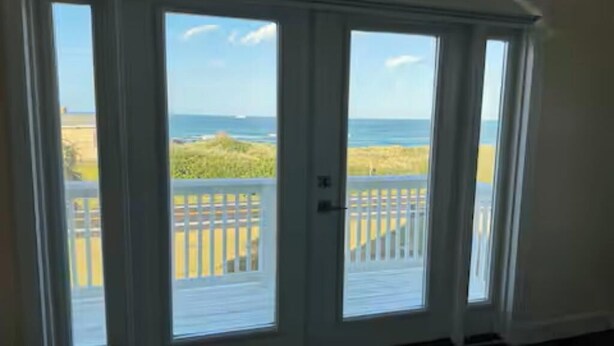 Ein Zimmer mit einer großen Schiebeglastür, die auf einen Balkon mit Meerblick führt.