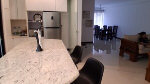 Una cucina moderna con un piano di lavoro in marmo, sedie nere e un frigorifero.