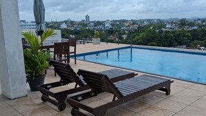 Area piscina con lettini e vista sulla città.