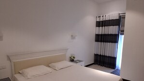 Una camera da letto con un letto, un comodino, una ventola a soffitto e una finestra con tende.
