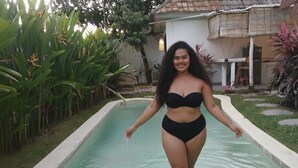 A person walking in a swimming pool with a house and garden in the background. - Rustic 2 bedrooms villa near Obsidian Gym (Bali)