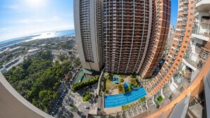 A high-rise residential building with multiple balconies, a rooftop pool, and a view of the coastline.