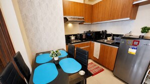 Una cocina moderna con armarios de madera, un refrigerador de acero inoxidable y un comedor con manteles individuales azules.