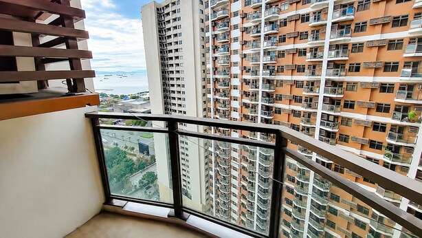A high-rise residential building with multiple balconies, large windows, and a view of the sea.