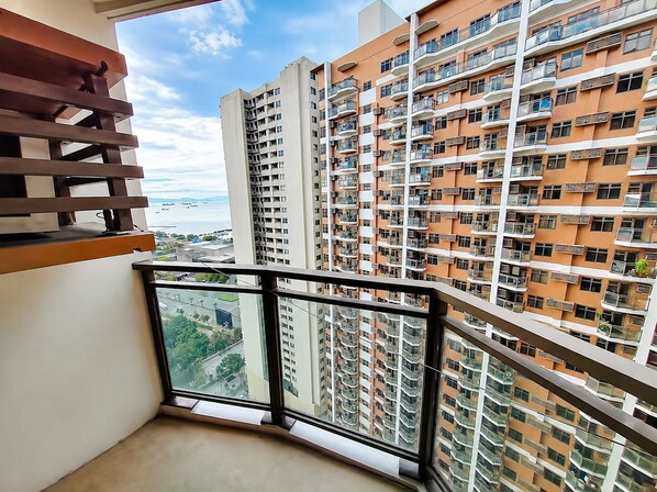 A high-rise residential building with multiple balconies, large windows, and a view of the sea.