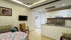 A compact room with a bed, a dining table, a TV, and a kitchenette. - Charming 1-bedroom apartment in Martil with WiFi (Martil)