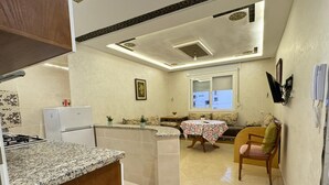 A kitchen with a granite countertop, a built-in oven, and a refrigerator. There is a dining area with a table and chairs. - Charming 1-bedroom apartment in Martil with WiFi (Martil)