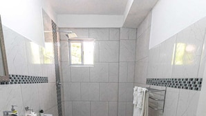 A bathroom with a toilet, sink, and shower area.