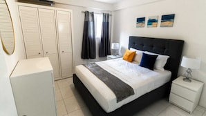 A bedroom with a bed, bedside tables, a wardrobe, and curtains.
