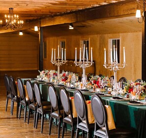 A banquet hall with long tables set for dining, adorned with floral centerpieces and candelabras.