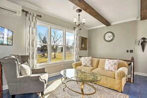 A living room with a sofa, armchair, and a glass coffee table.