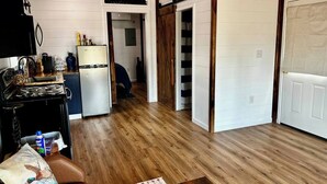 Una cucina compatta con frigorifero, piano cottura e pensili in legno. Si vede anche un'area pranzo con tavolo e sedie.