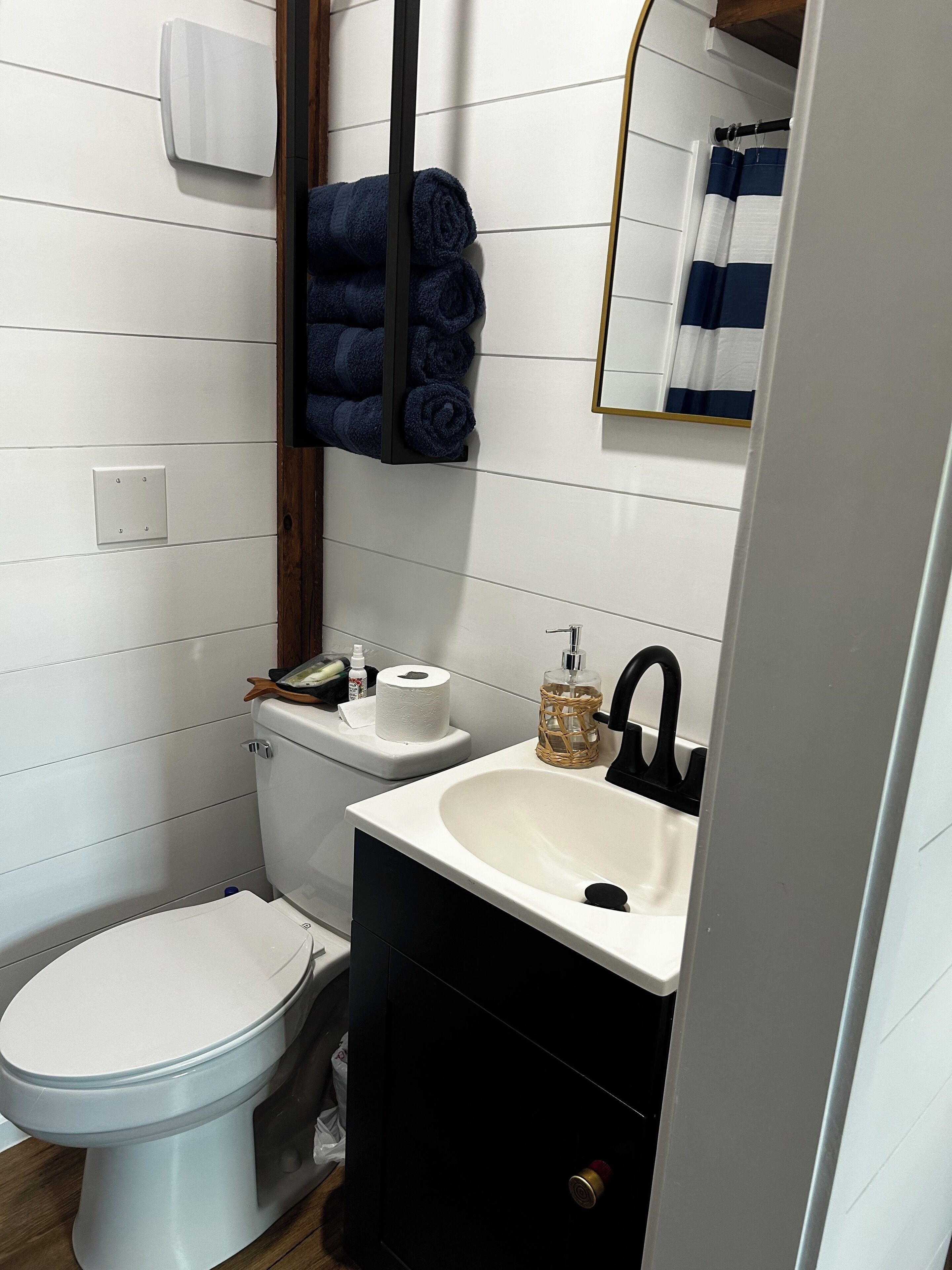 Un baño moderno con inodoro, lavabo y un perchero con toallas enrolladas.