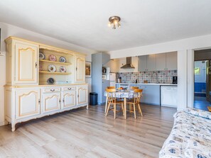 A spacious kitchen with a dining area, wooden cabinets, and a tiled backsplash. - Les Cigales by Interhome (Cavalaire)