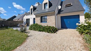 A modern two-story house with a stone facade, a blue garage door, and a gravel driveway. - l'Etoile de Mer - SARZEAU (SARZEAU)