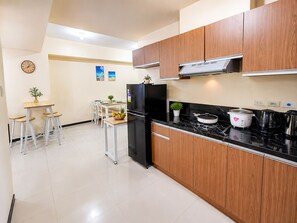 Eine moderne Küche mit einem schwarzen Kühlschrank, Holzschränken, einer Marmorarbeitsplatte und einem Essbereich mit Tisch und Stühlen.