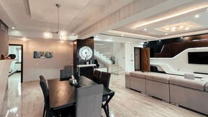 A modern living room with a dining area, a large wall-mounted TV, and a staircase leading to an upper level. - DELUXE MIRAFLORES DUPLEX (Tangier)