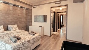 A bedroom with a bed, a nightstand, a dresser, and a mirror. There is a hallway leading to another room. - DELUXE MIRAFLORES DUPLEX (Tangier)