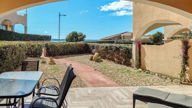 Ein möblierter Außenbereich mit Terrasse, Weg und Blick auf das Meer.