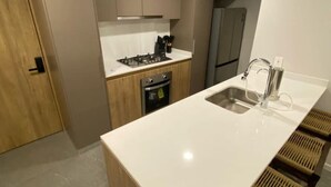 Une cuisine moderne dotée d’un îlot central, d’appareils électroménagers en acier inoxydable et d’un four encastré.