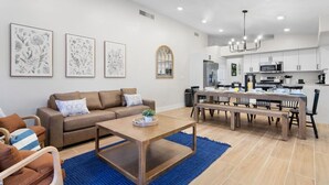 A modern living room with a sofa, coffee table, and dining area with a bench.