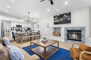 Una sala de estar moderna con comedor, cocina y chimenea.