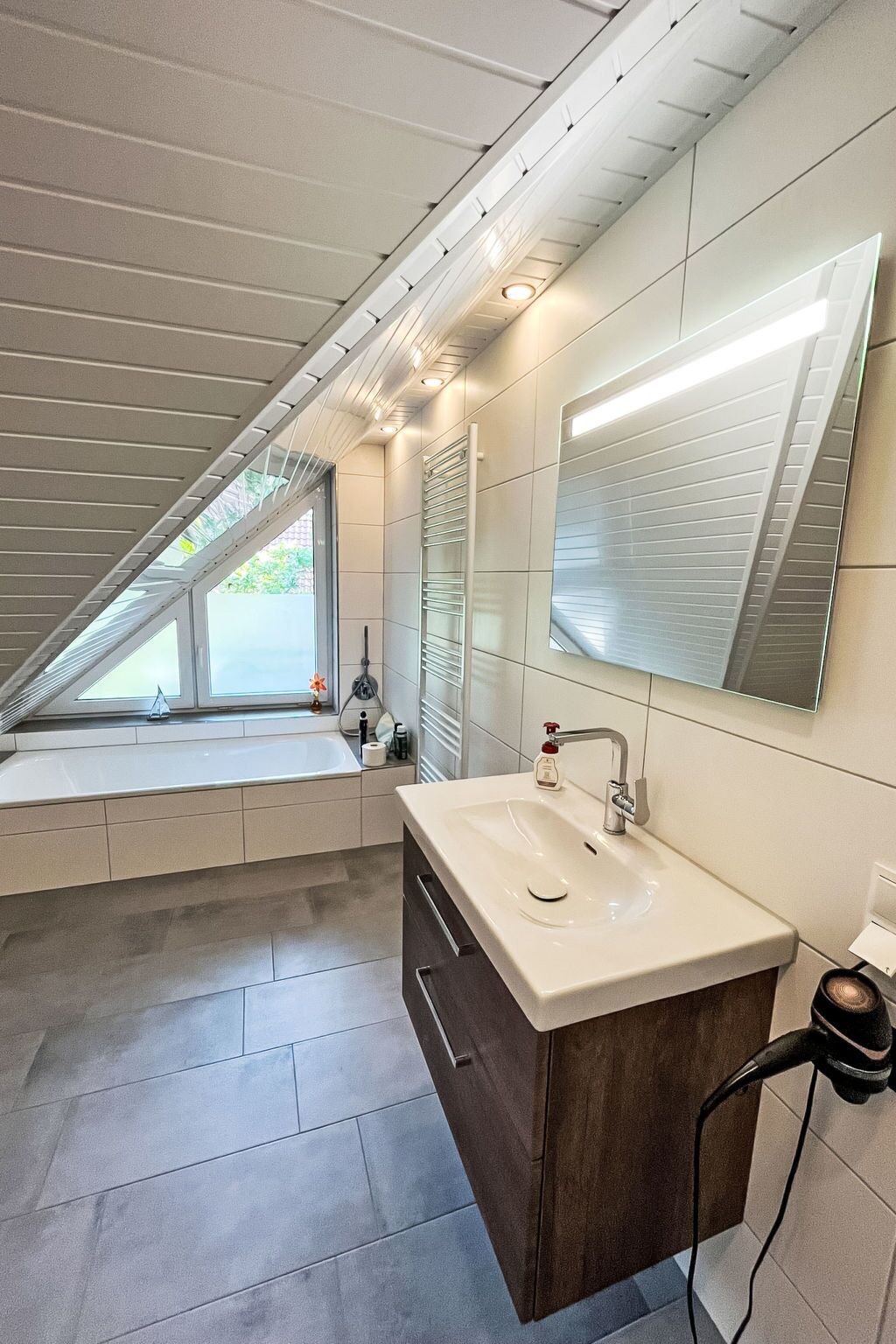 A modern bathroom with a large window, a built-in sink, and a mirror.
