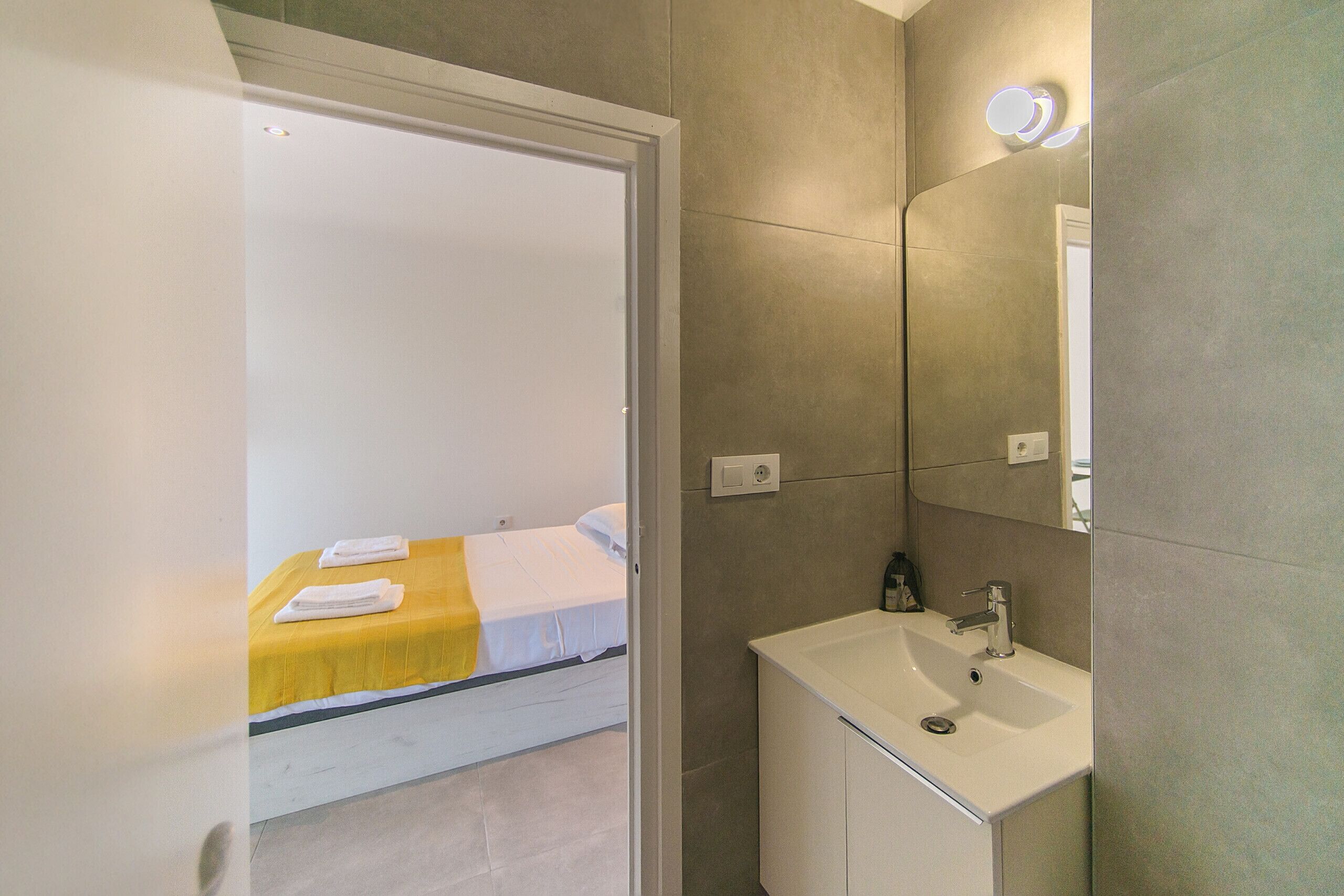 Een hotelkamer met een bed, een badkamer met een wastafel en een spiegel.