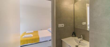 A hotel room with a bed, a bathroom with a sink, and a mirror.