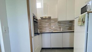 Una cocina moderna con gabinetes blancos, horno empotrado y microondas.