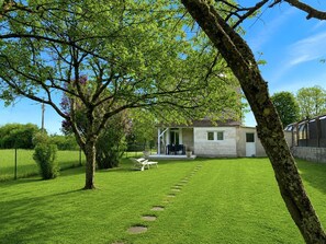 Uma casa com fachada de pedra, gramado e um caminho que leva à entrada.